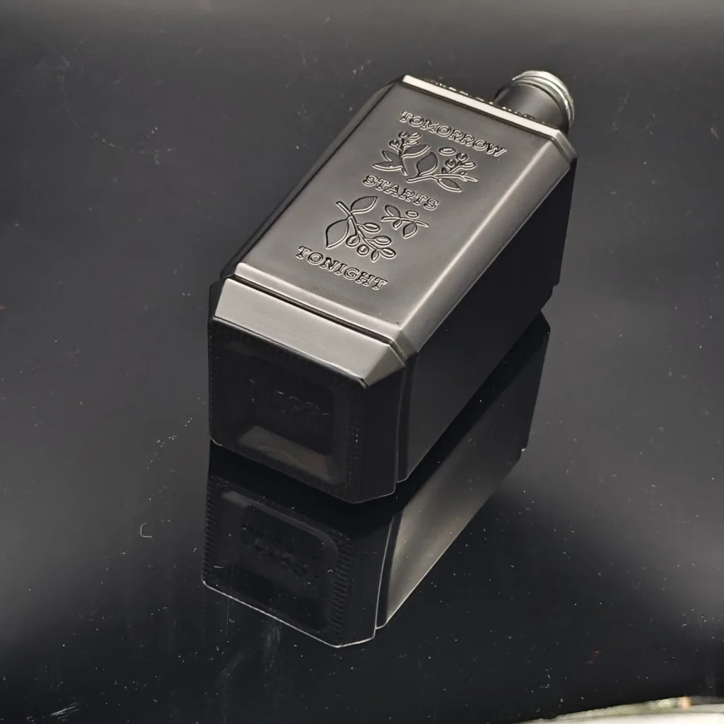 A rectangular black glass spirits bottle showcasing sharp 3D embossed floral patterns and custom capitalized typography stating Tomorrow Starts Tonight on a metallic satin finish.