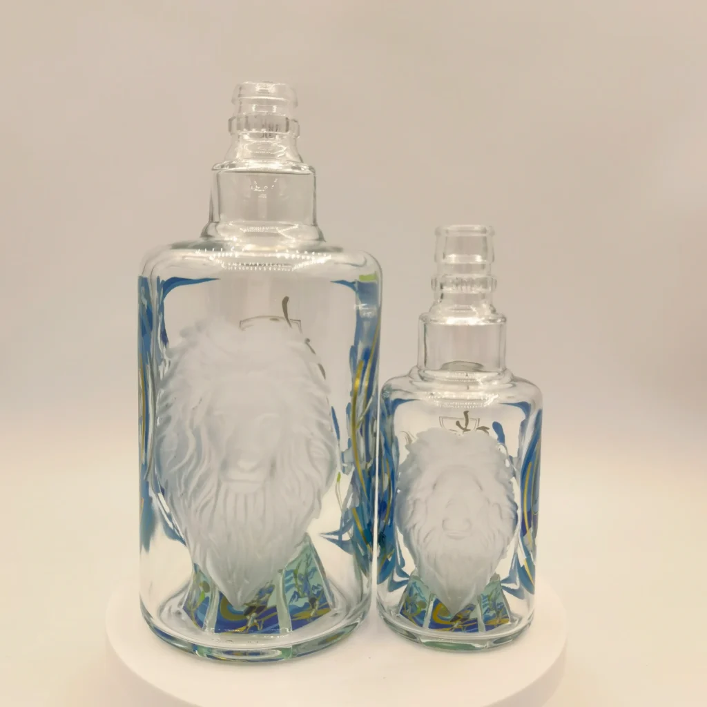 cTwo clear glass spirits bottles showcasing a prominent 3D mold-embossed lion head feature with a frosted sandblasted finish, surrounded by intricate blue and gold custom decal printing.