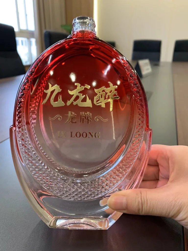 Customized glass spirit decanter with premium red gradient spray coating and custom embossed gold foil decal branding.