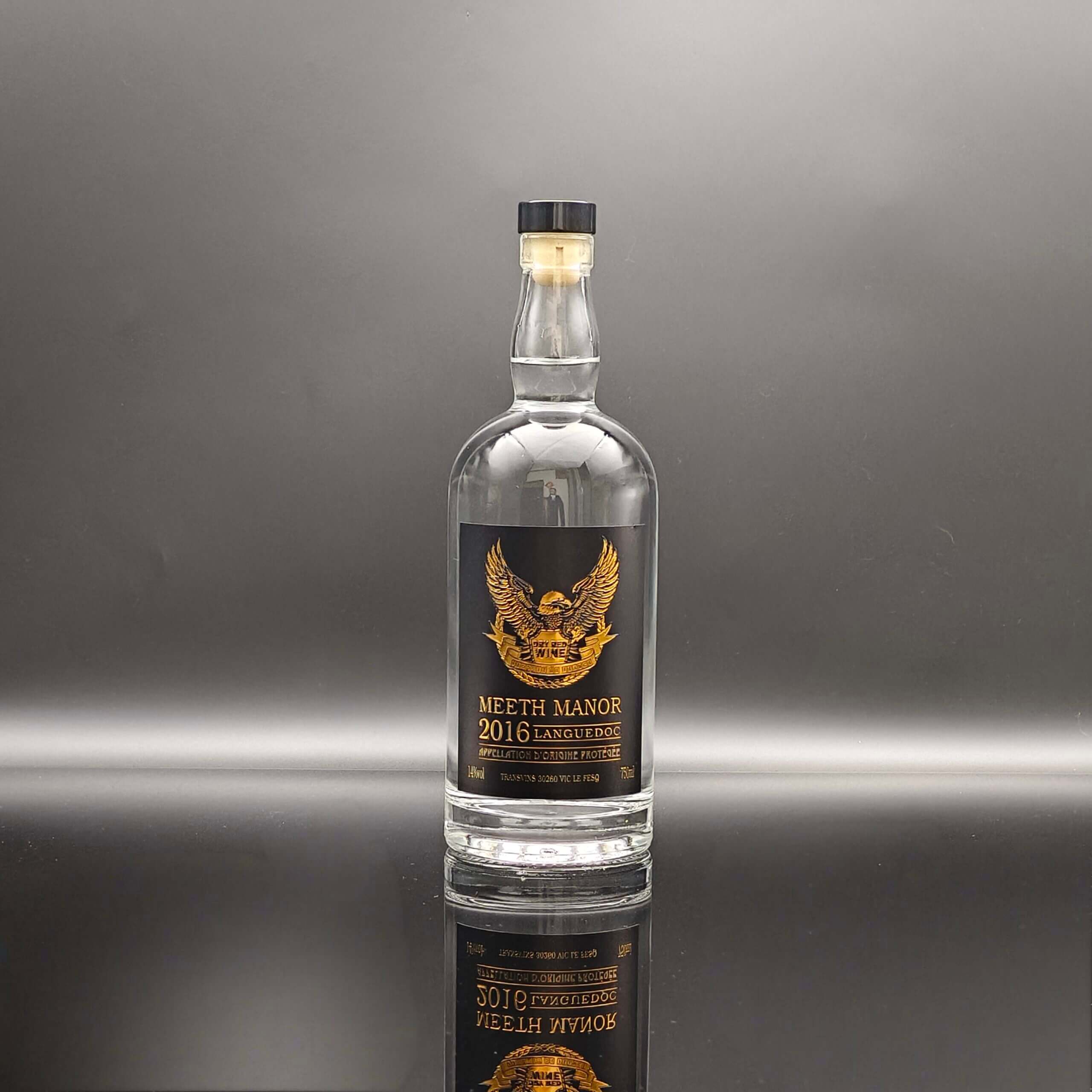 Custom extra flint glass liquor bottle with bespoke gold printing label and T-top cork closure.