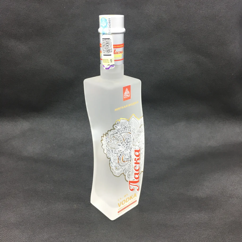 An elegant, wave-shaped custom vodka glass bottle featuring a premium full-body acid frosting finish overlaid with a multi-color water slide decal of intricate white and gold patterns.