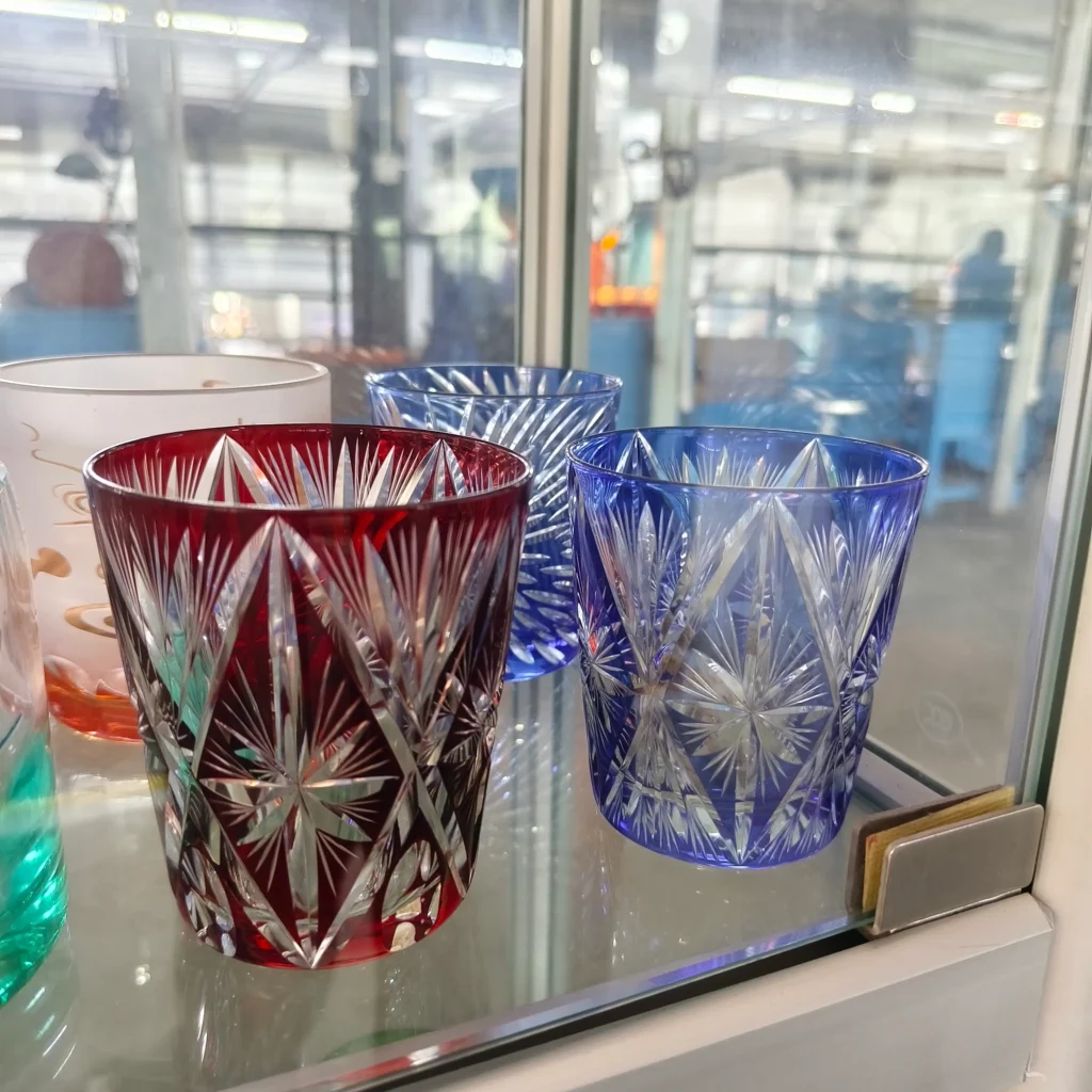 Premium ruby red and cobalt blue overlay glass tumblers featuring intricate hand-engraved diamond starburst cut patterns that reveal the transparent clear glass underneath.