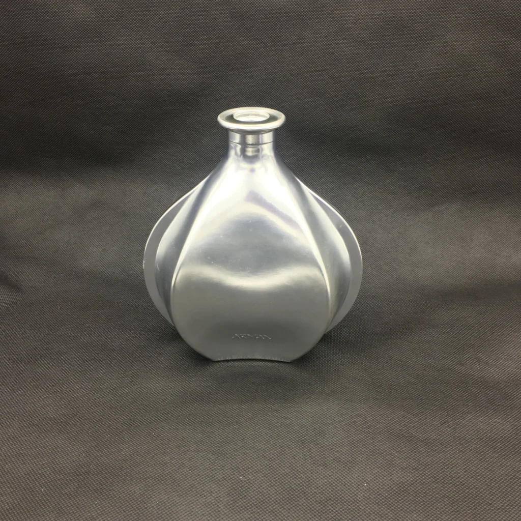 A custom geometric glass bottle featuring a premium matte silver electroplating finish, showcasing a non-reflective satin chrome metallic texture on a curved profile with embossed details.