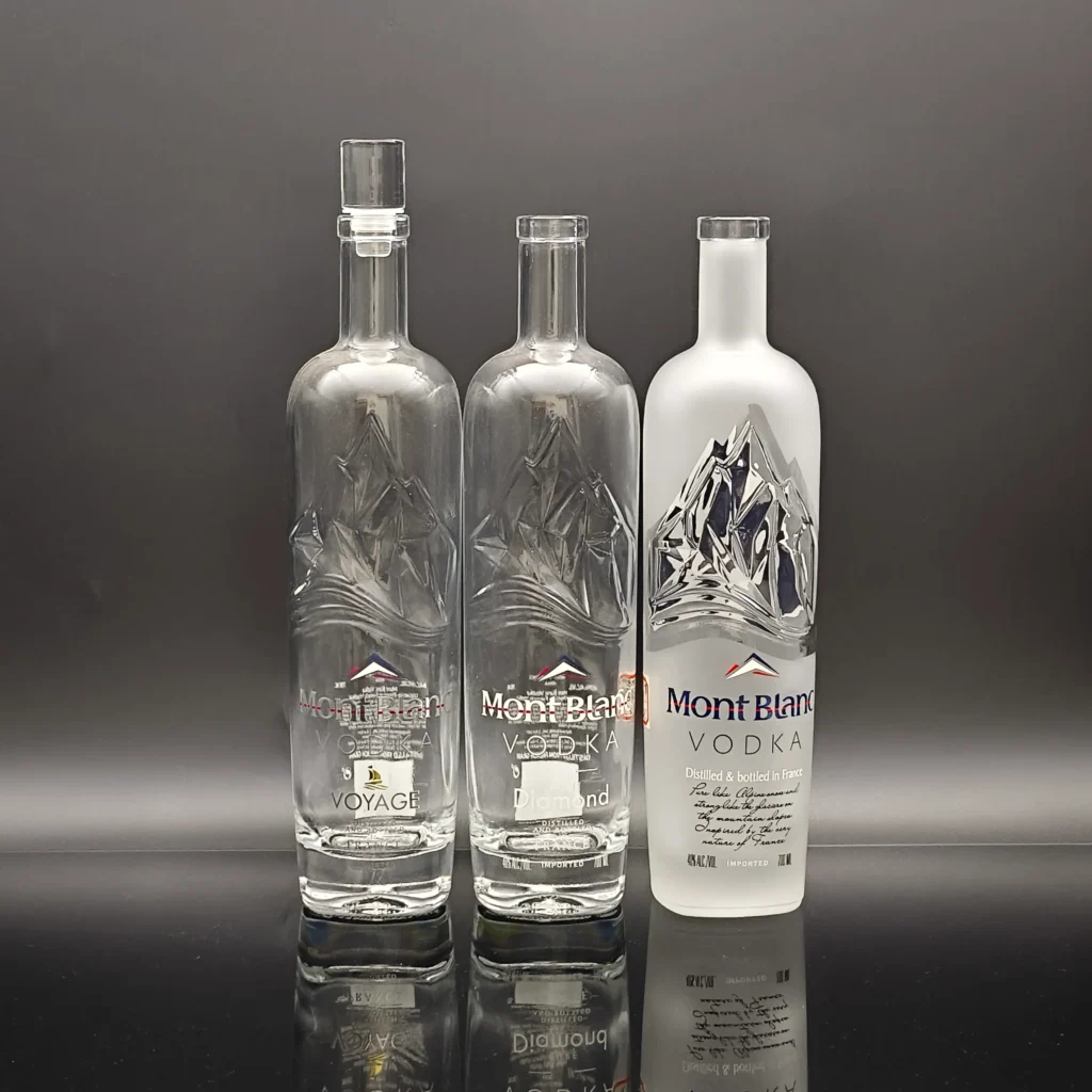 A commercial comparison between clear super flint glass bottles and a partially frosted vodka bottle, highlighting the sharp contrast between transparent embossed ice-mountain reliefs and silk-smooth matte acid-etched surfaces.