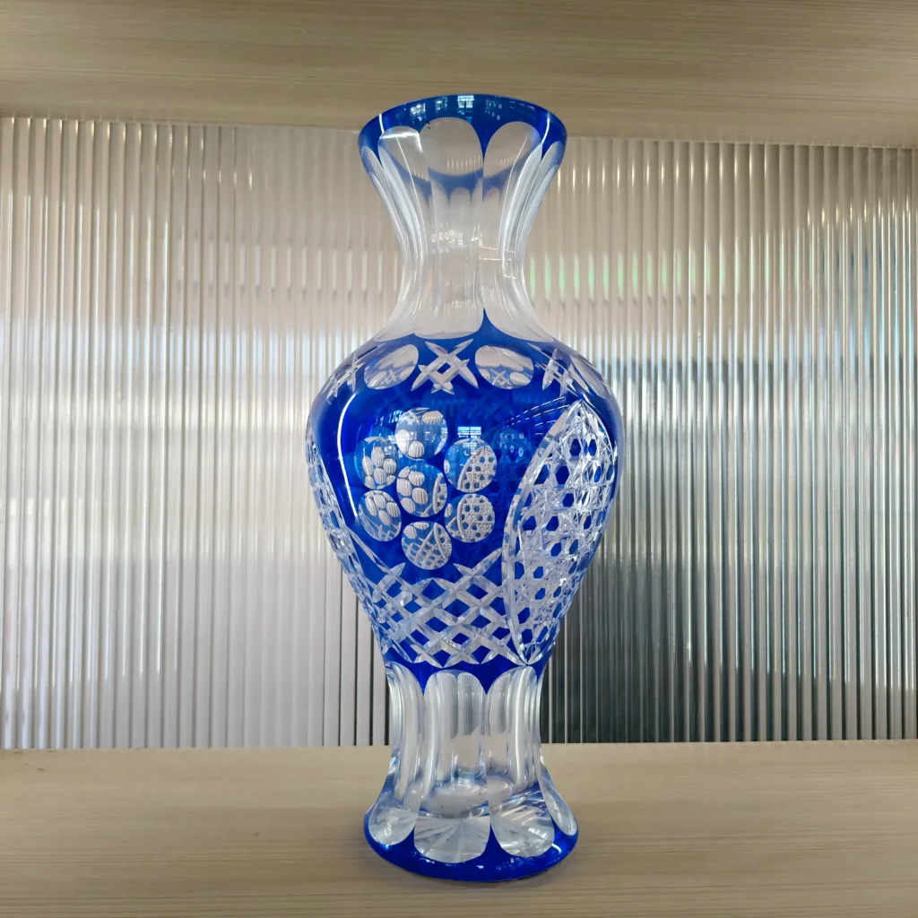 An export-quality custom glass decanter bottle featuring traditional hand-cut cobalt blue overlay glass engineering, showcasing intricate hand-engraved diamond geometric patterns and floral motifs that reveal the transparent clear glass underneath.