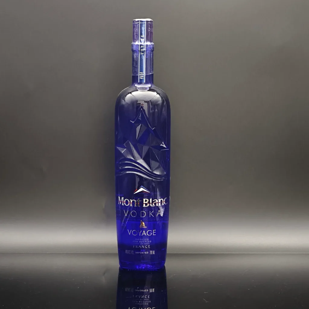 A premium super flint vodka glass bottle finished in a translucent royal blue spray coating, featuring precision multi-color branding decals and an embossed mountain relief.